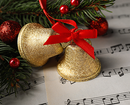 Hymn music sheet with golden glitter bells tied together with a red ribbon.