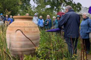 Adults standing beside an urn surrounded by grasses.