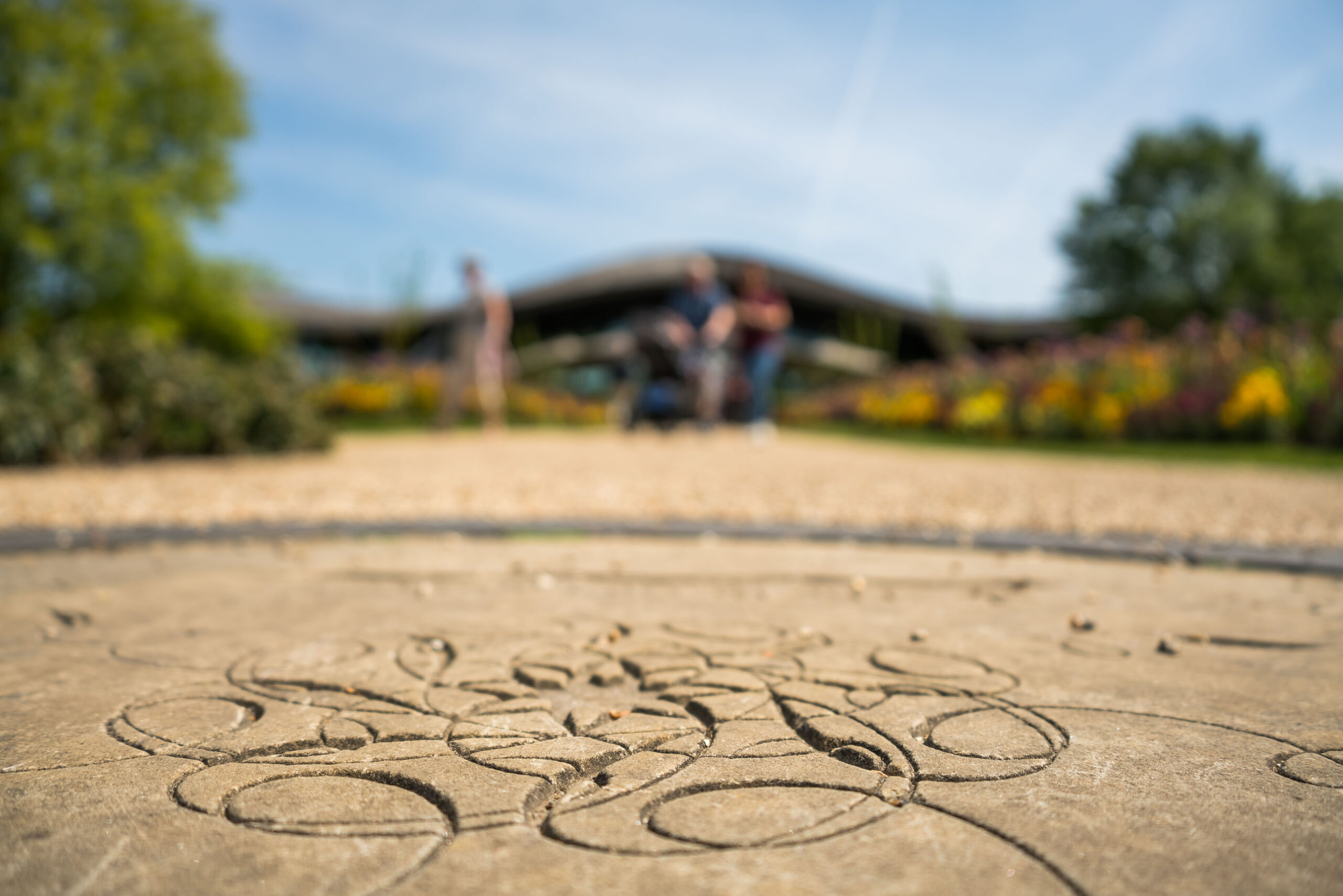 The Savill Garden plaque with The Savill Garden Visitor Centre behind.