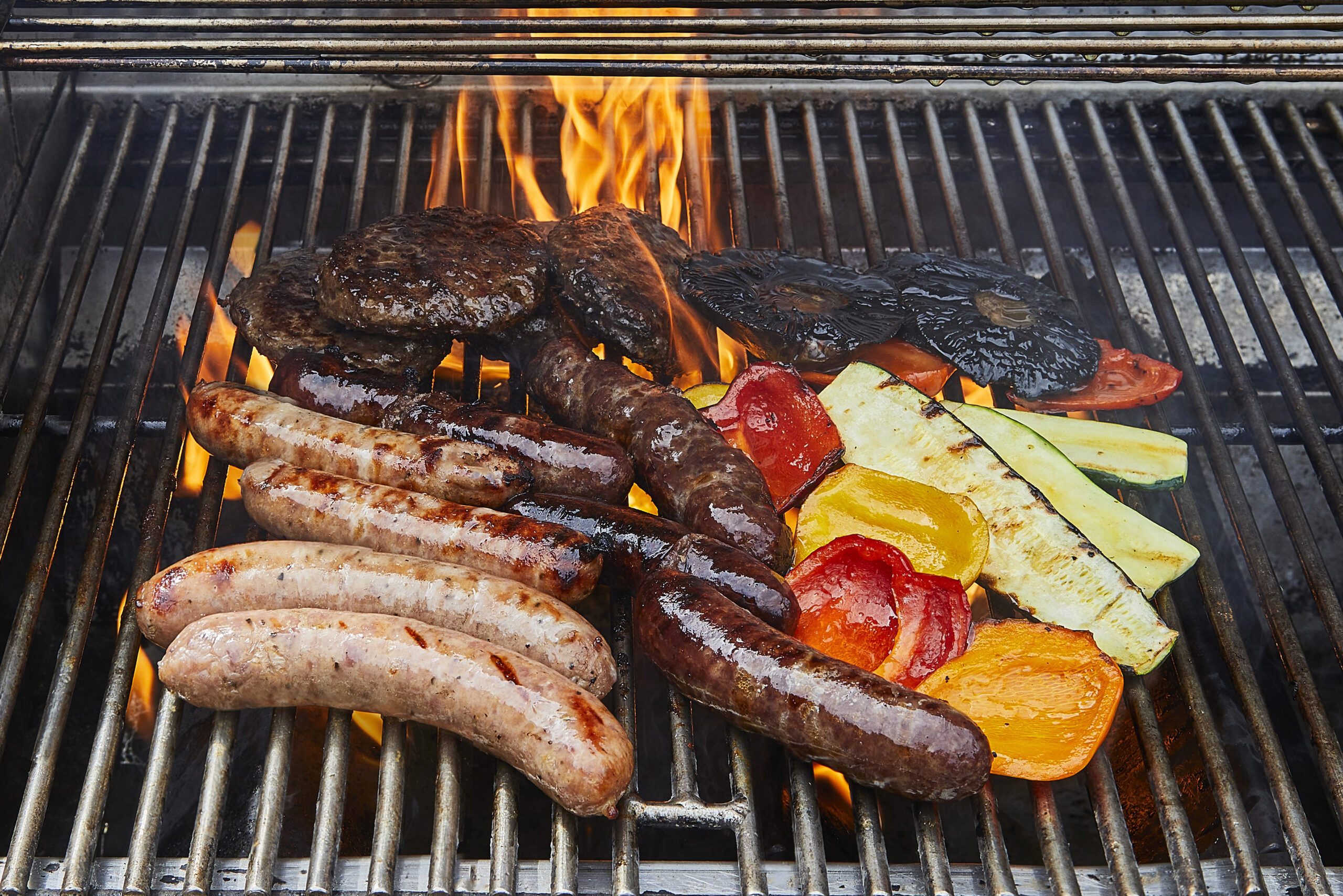 A selection of meat and vegetables on a barbecue grill.
