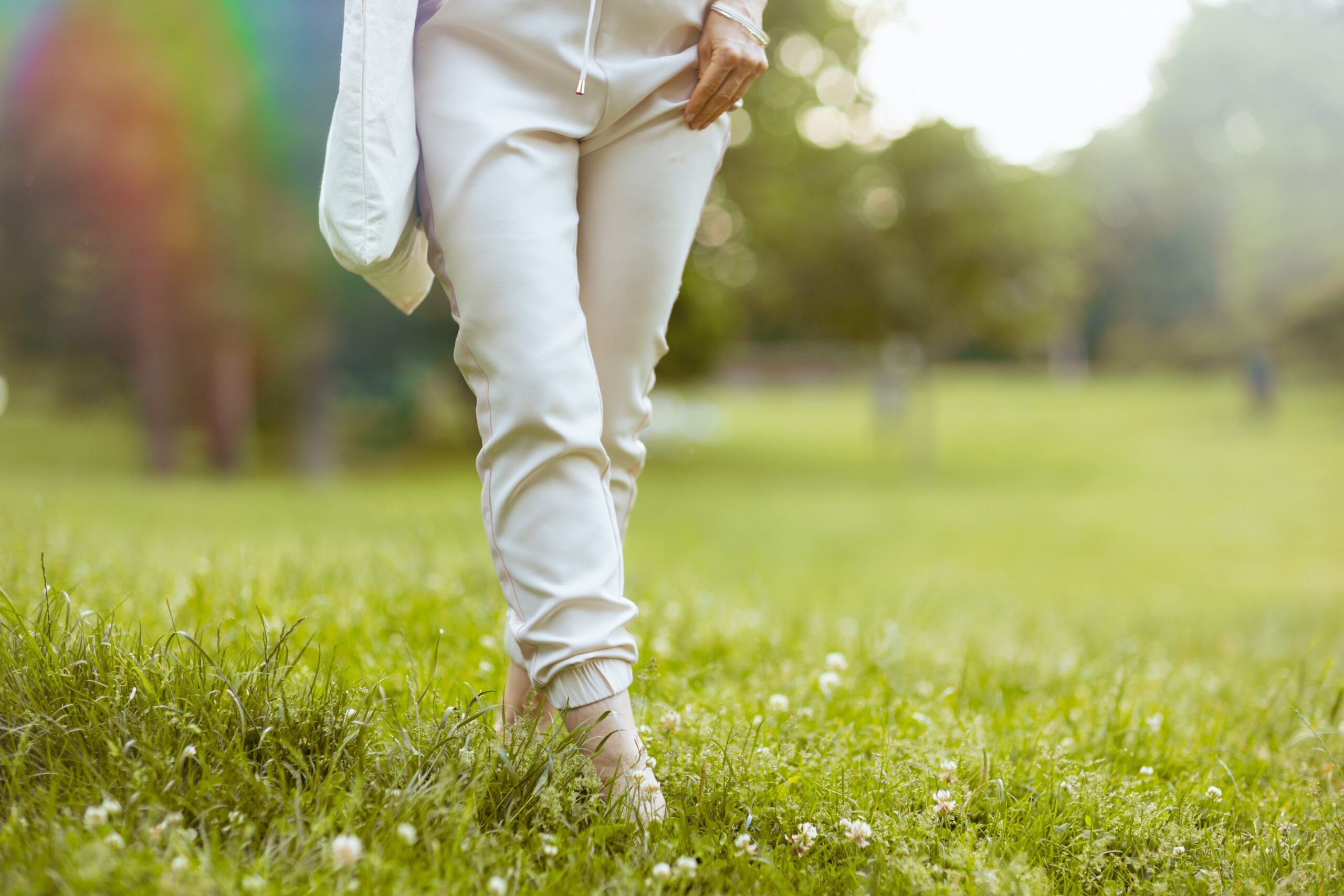 Adult wearing light coloured clothes, walking through a field of grass.