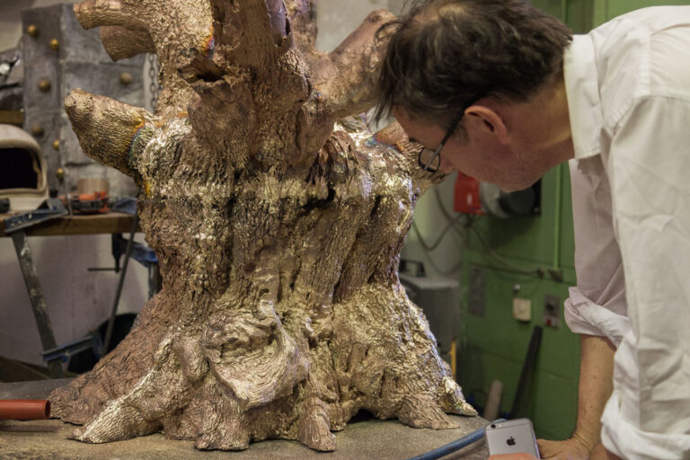 A person inspecting a bronze cast of the Signing Oak.