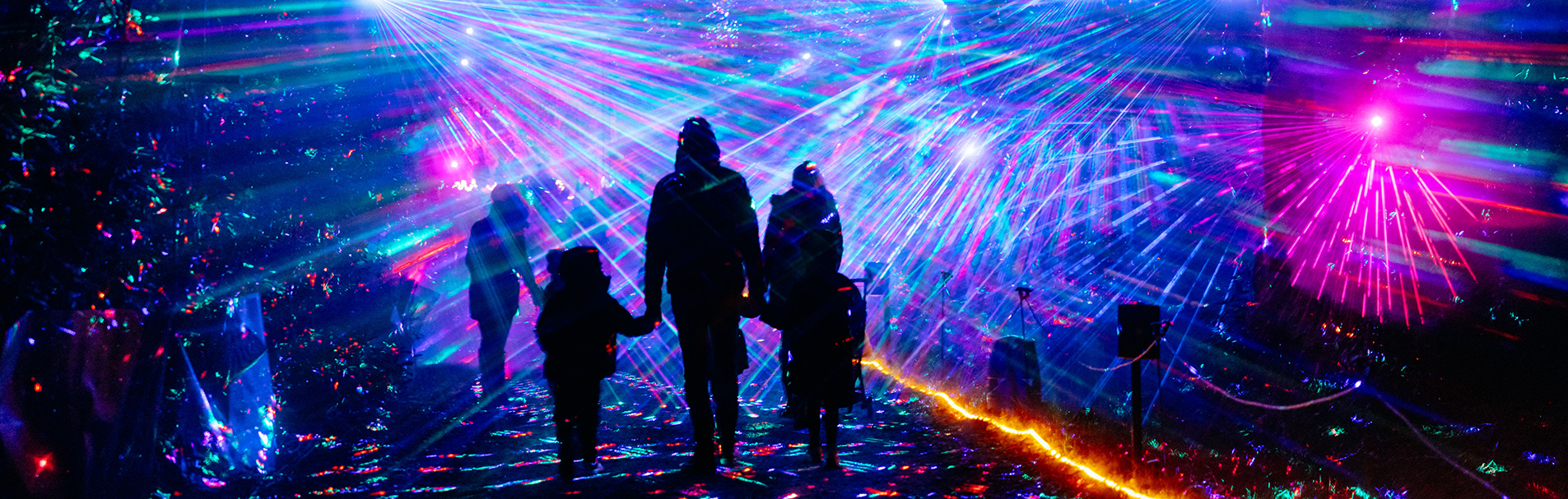 Family walking through a stream of colourful lights.