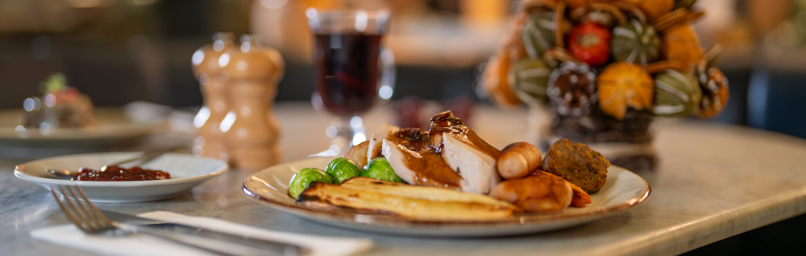 Christmas table setting with a glass of red wine and decorations.