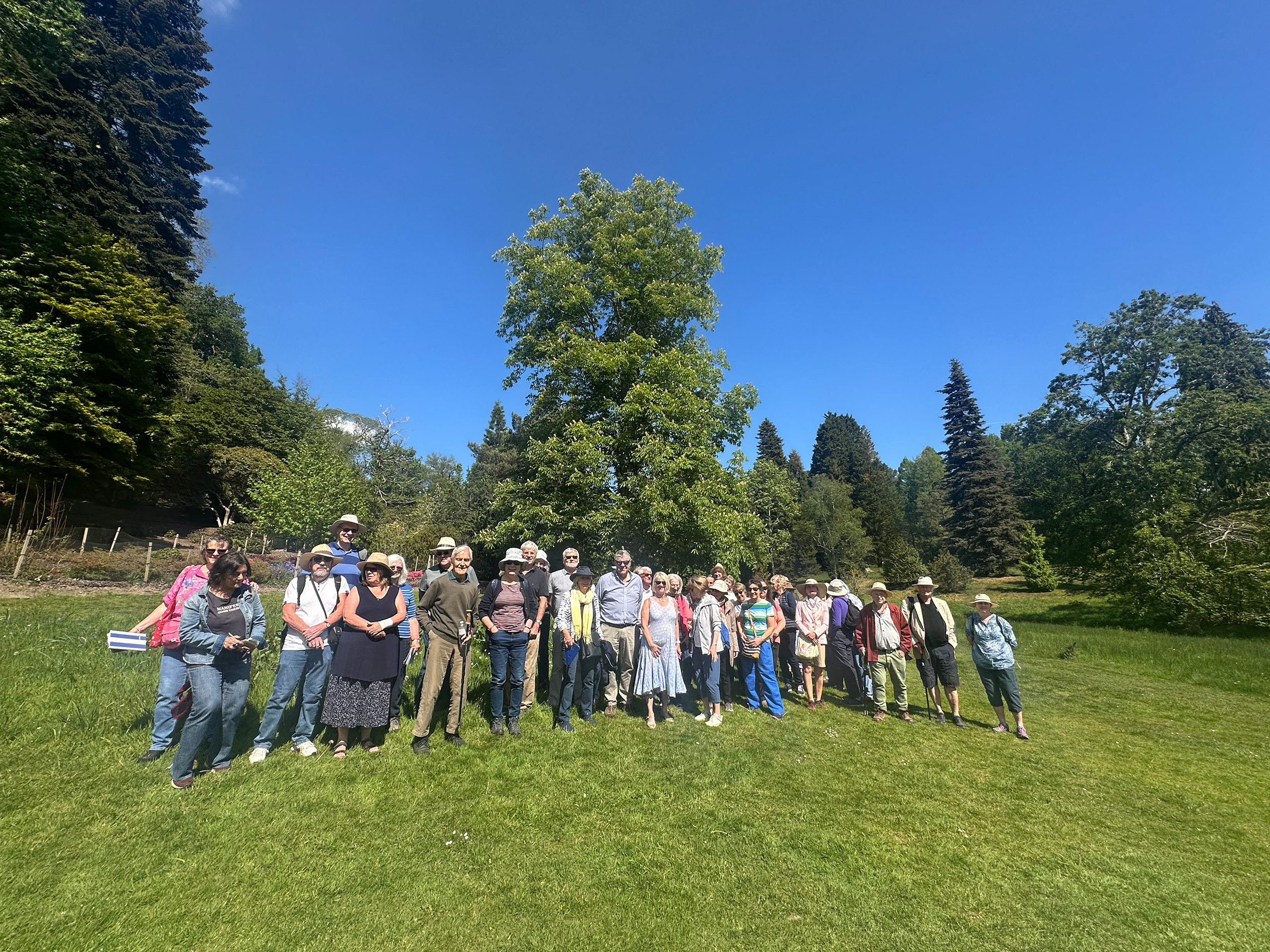 A group of people standing in a line for a photograph with trees behind.