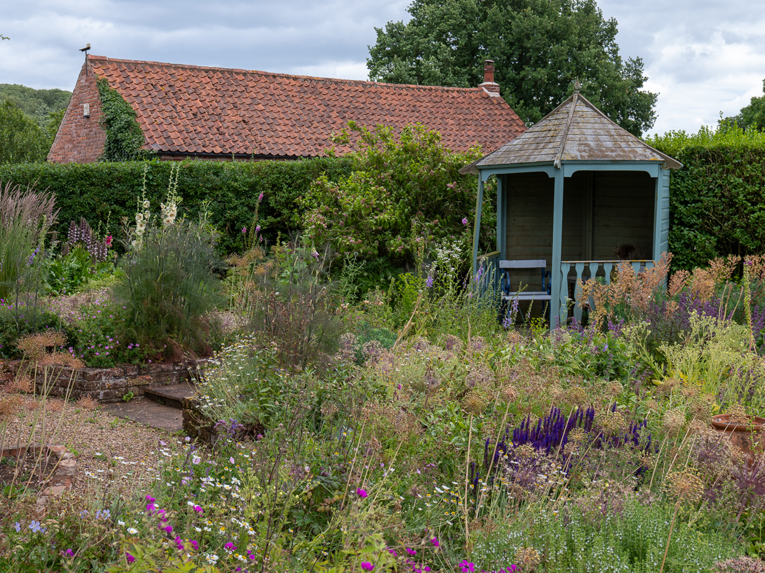 A small summerhouse surrounded by spring shrubs.
