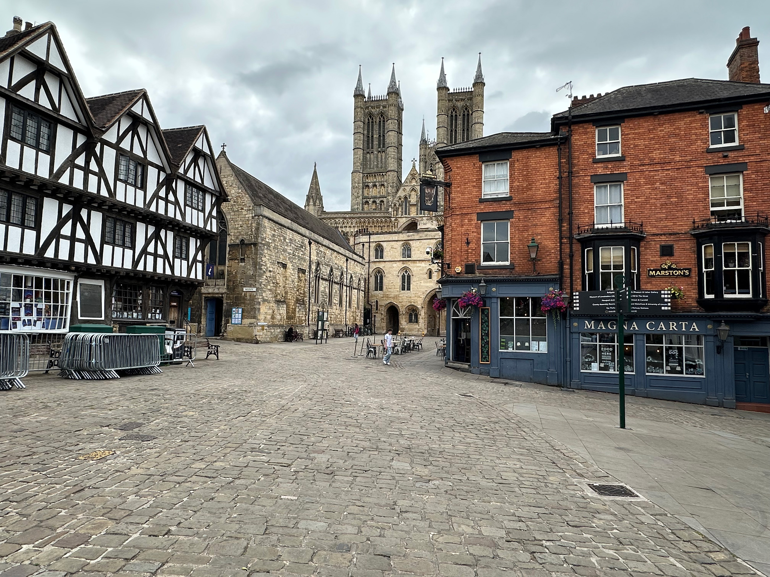 A cobbled street with historic brick and black and white buildings, with Lincoln Cathedral in the distance.