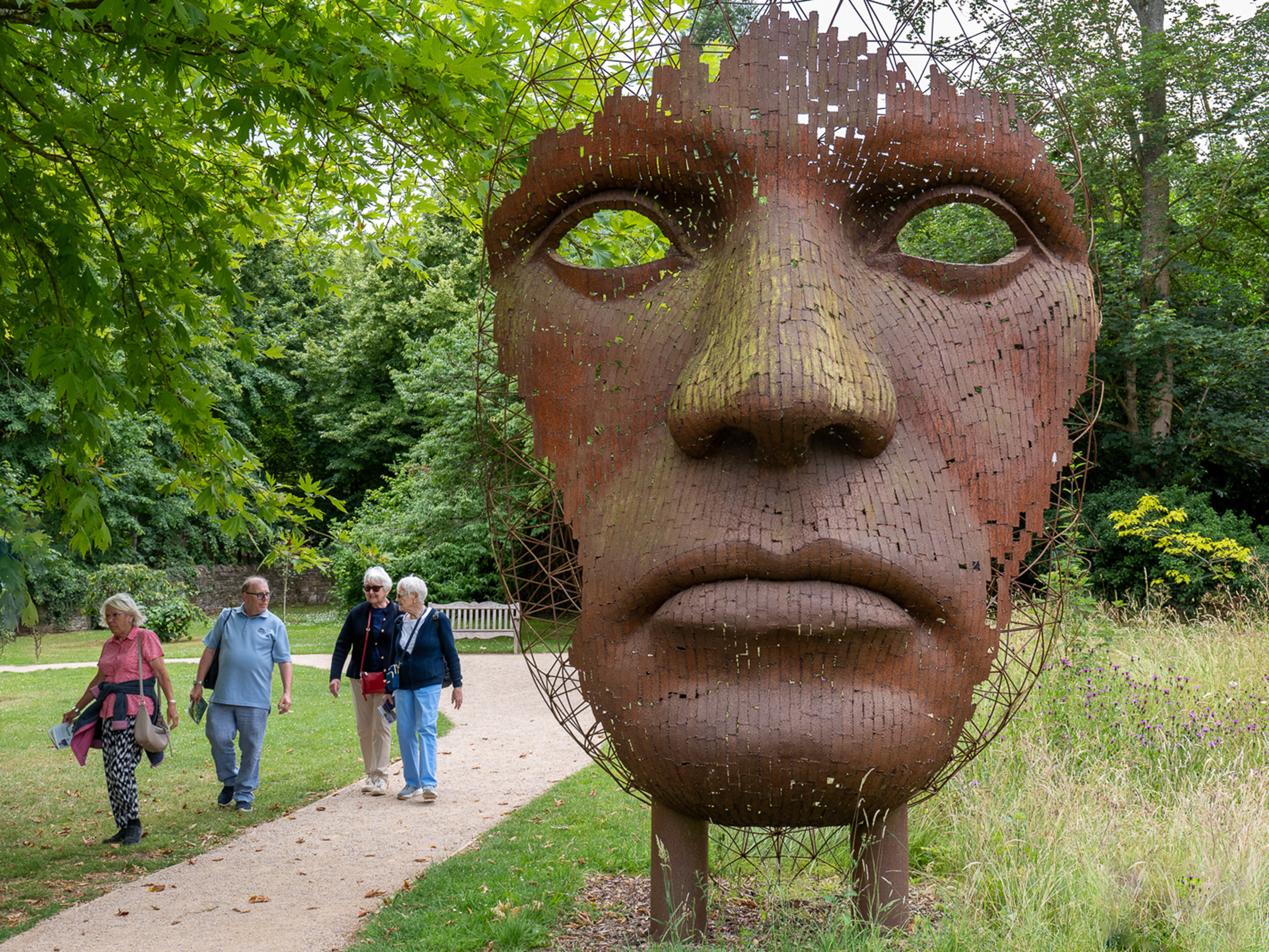 A large sculpture of a human face beside a footpath.