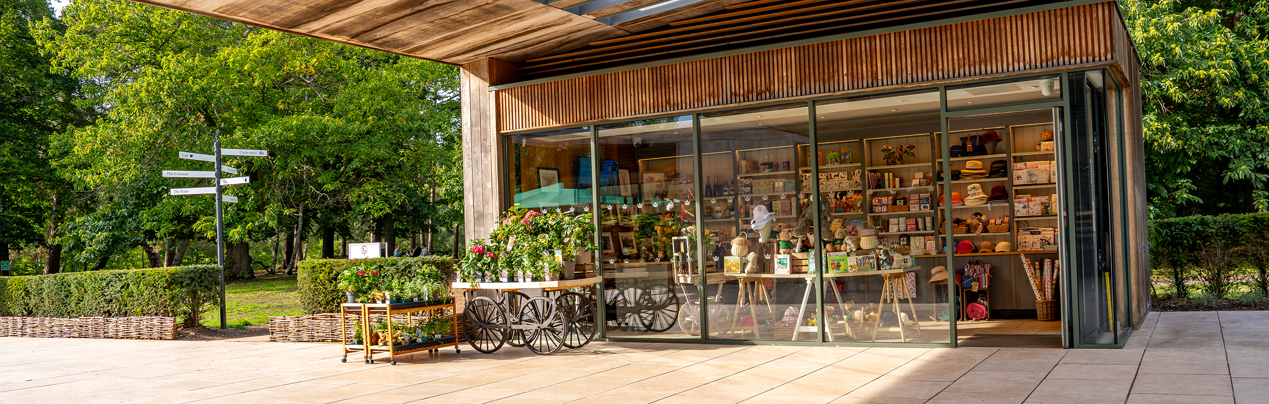 The exterior of the Virginia Water Gift Shop with large windows into the shop, with an outdoor plant trolley.