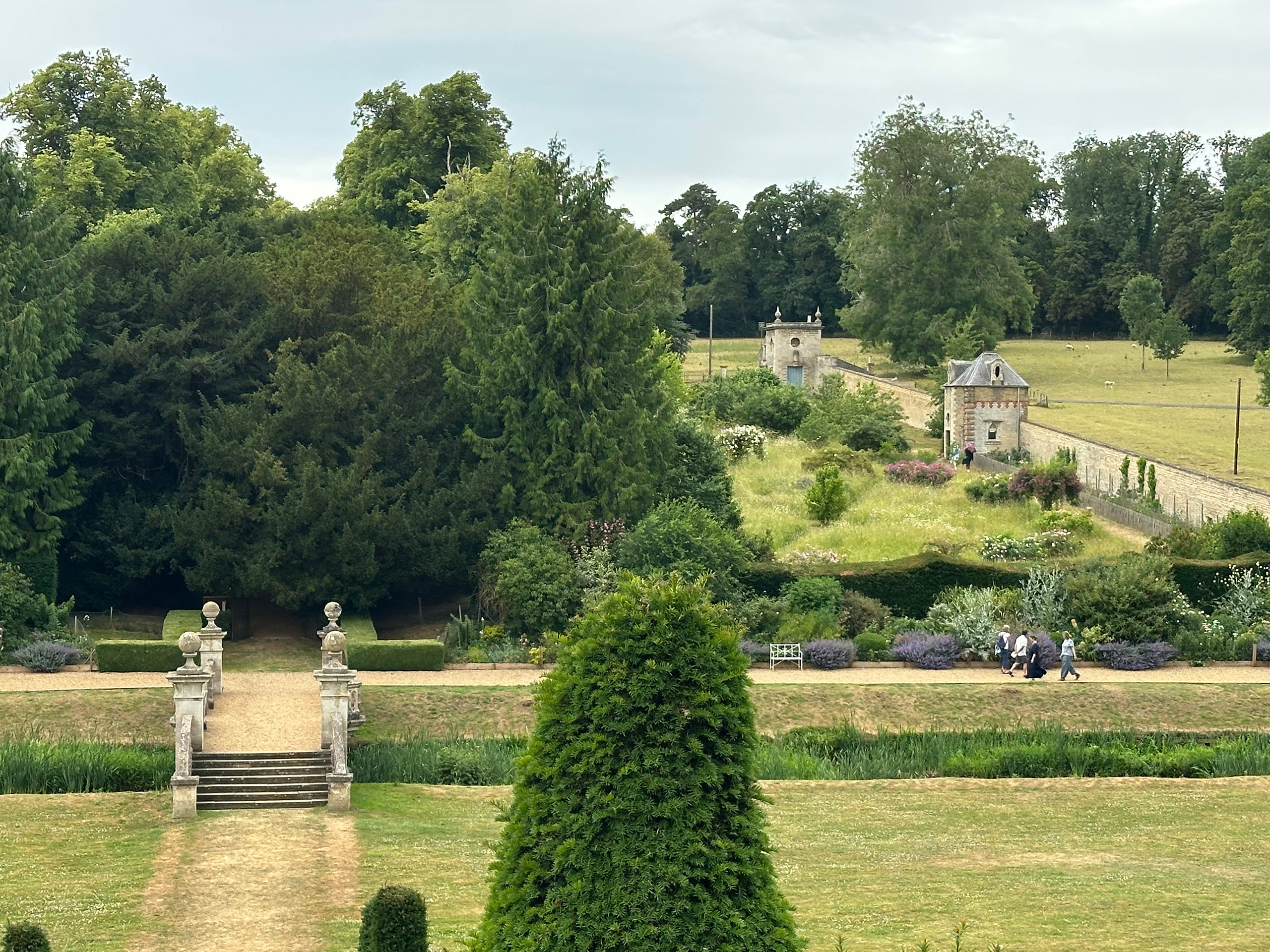 Overlooking a rectangular lawn with colourful borders and surrounded by a wall.