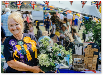 A person holding a flower display with several rosettes pinned to them