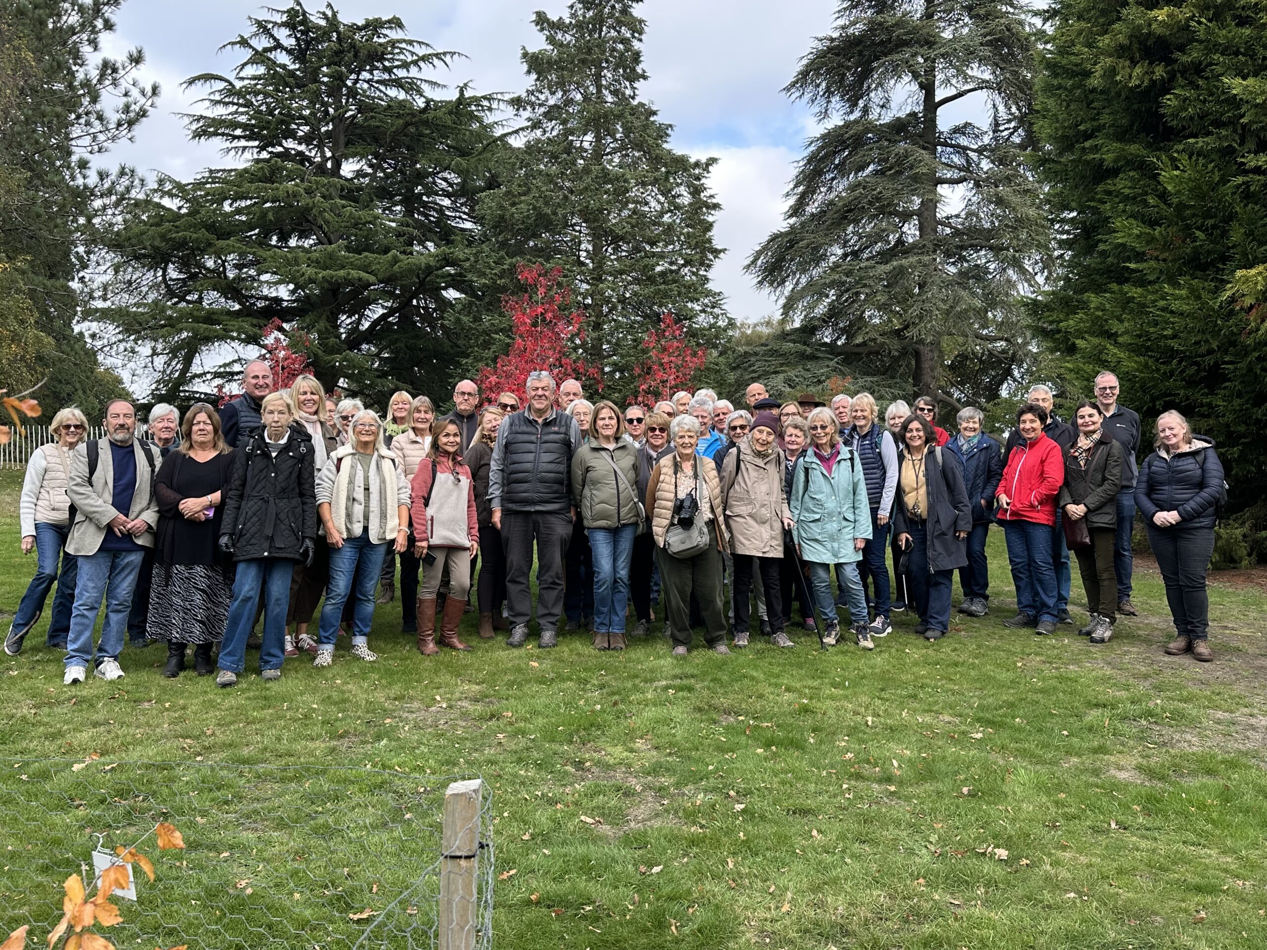 The Friends of The Savill Garden photographed with John Anderson, Keeper of The Gardens in front of a tall green trees.