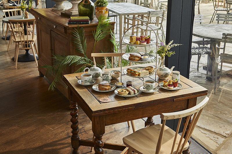 An Oak table set with an Afternoon Tea of Sandwiches, Scones, Cakes and Tea.