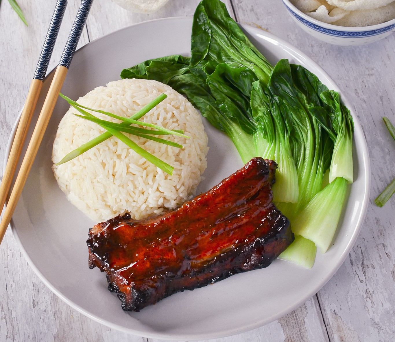 Char Siu Pork Ribs with Jasmin Rice, Pak Choi, garnished with sliced Spring Onions.