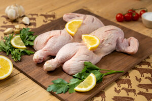 Spatchcocked Chicken with seasoning and lemon slices.