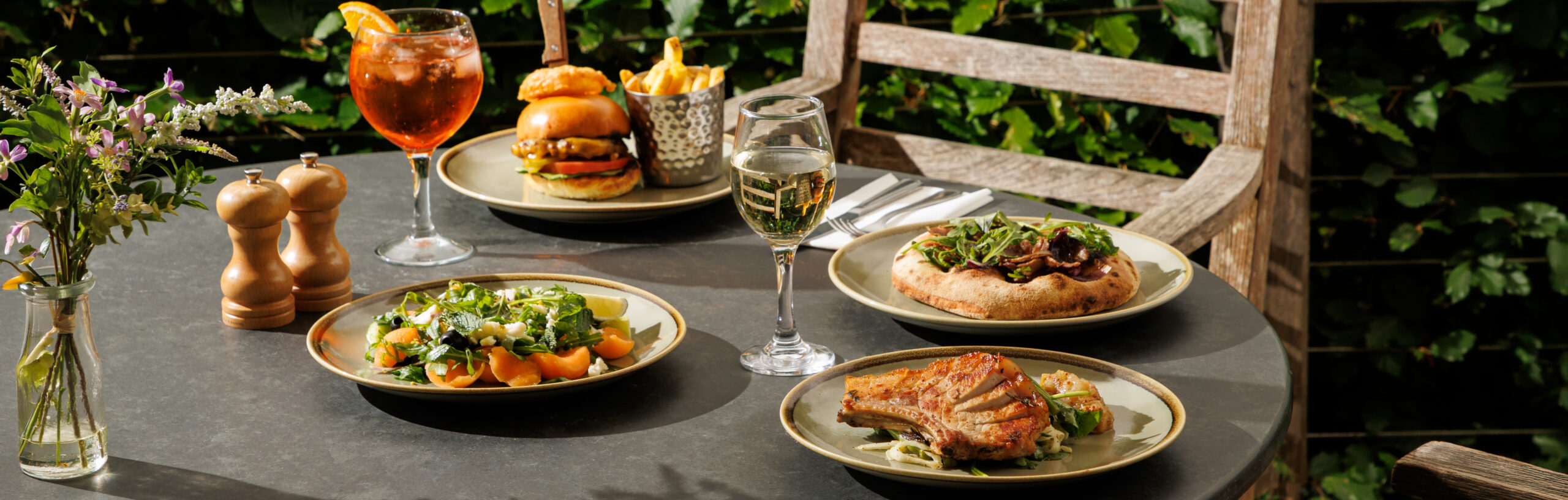 Table dressed with 4 plates of food with summer drinks.
