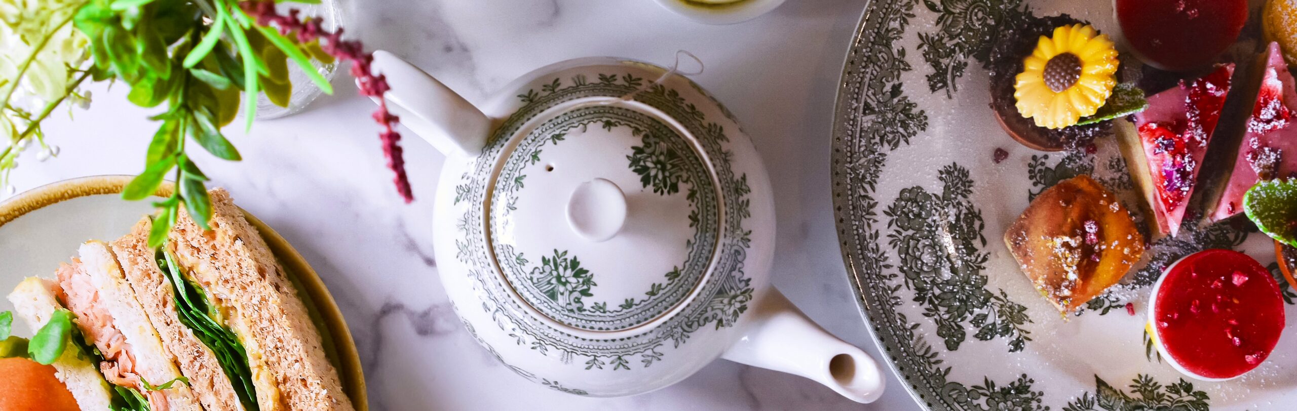 A marble table laid with Afternoon Tea sandwiches and treats.