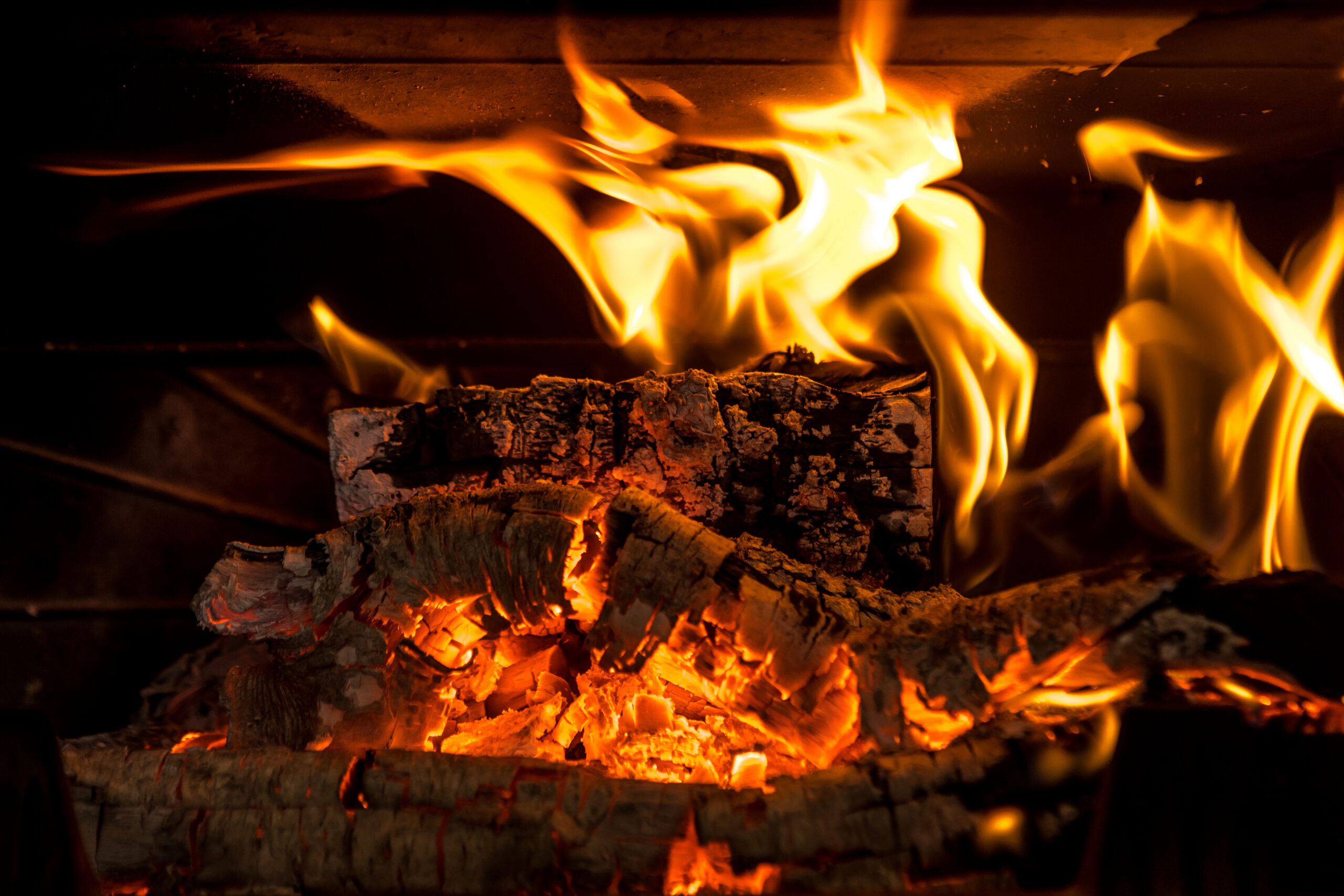 Logs burning in the fire of a fireplace with embers.