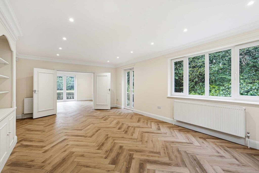 Spacious kitchen and dining area with herringbone flooring, large windows and garden views.