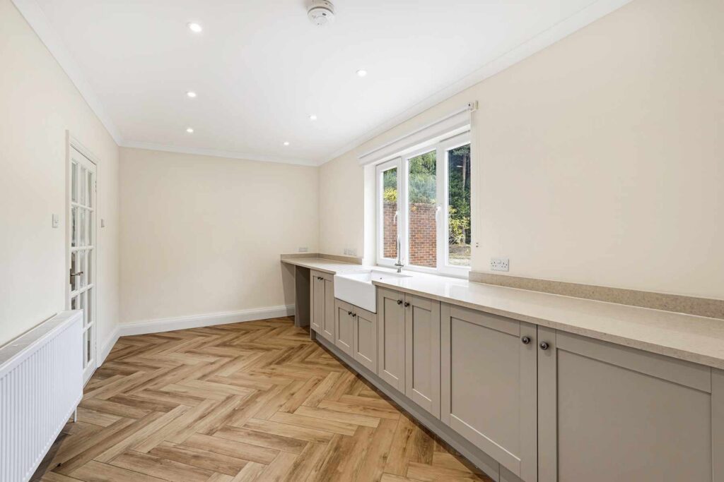 Utility room with fitted cabinetry, worktops, farmhouse sink and space for appliances.