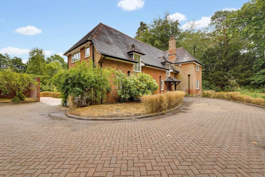 Detached brick family home set within a spacious driveway and surrounded by mature woodland.