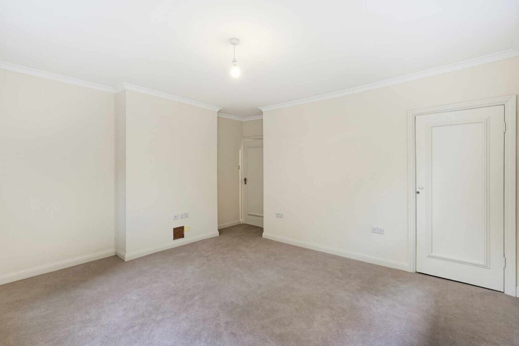 Spacious unfurnished bedroom with neutral décor, fitted carpet and doors leading to adjoining rooms.
