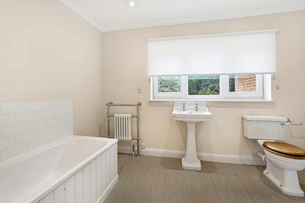 Family bathroom featuring a bath, pedestal basin, WC and window overlooking the grounds.