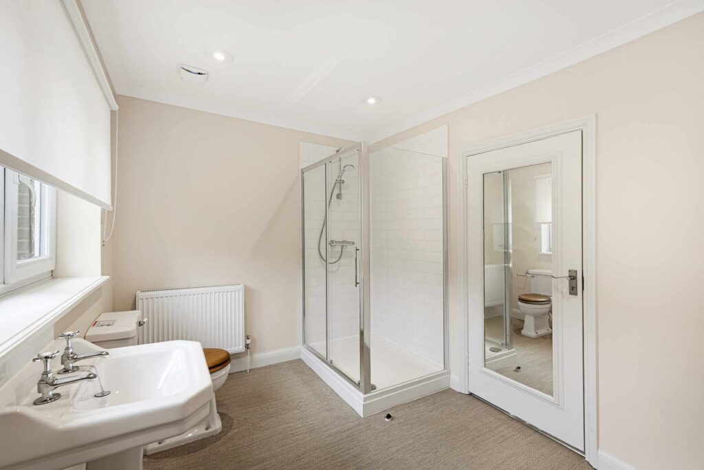 Contemporary shower room with walk-in shower, pedestal basin, WC and full-height mirror.