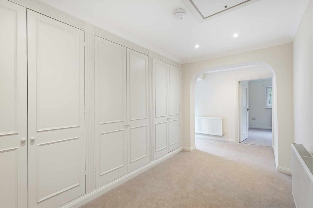 Dressing room with a wall of fitted wardrobes and access to adjoining accommodation.