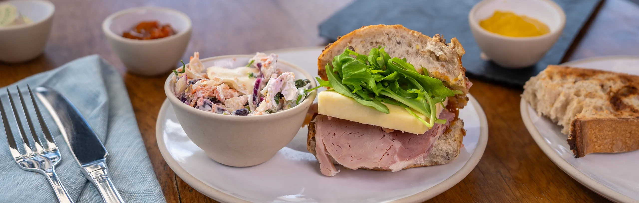 Ham and Cheese sandwich with a side bowl of coleslaw.
