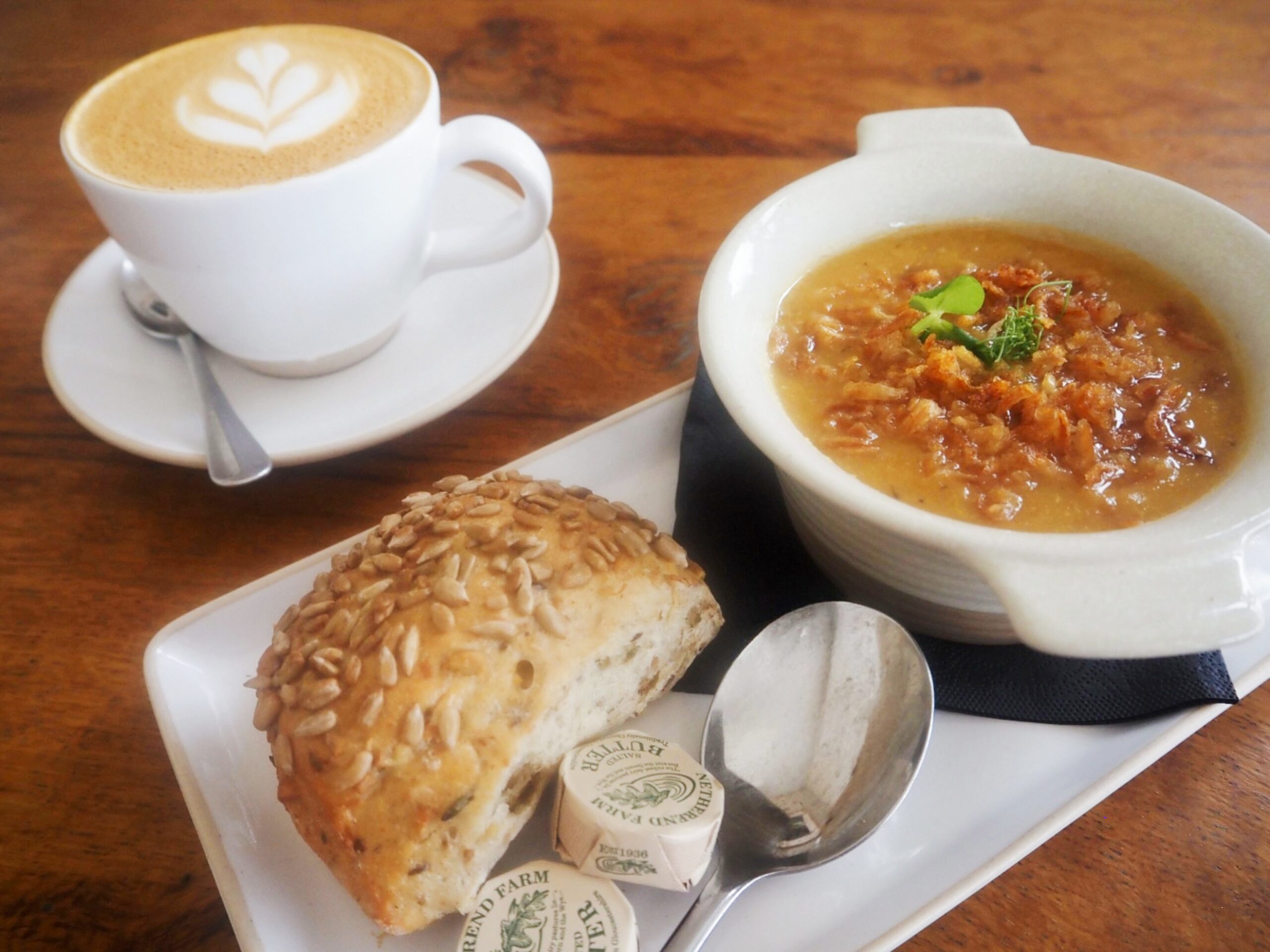 Soup with a bread roll, butter and a Cappucino.