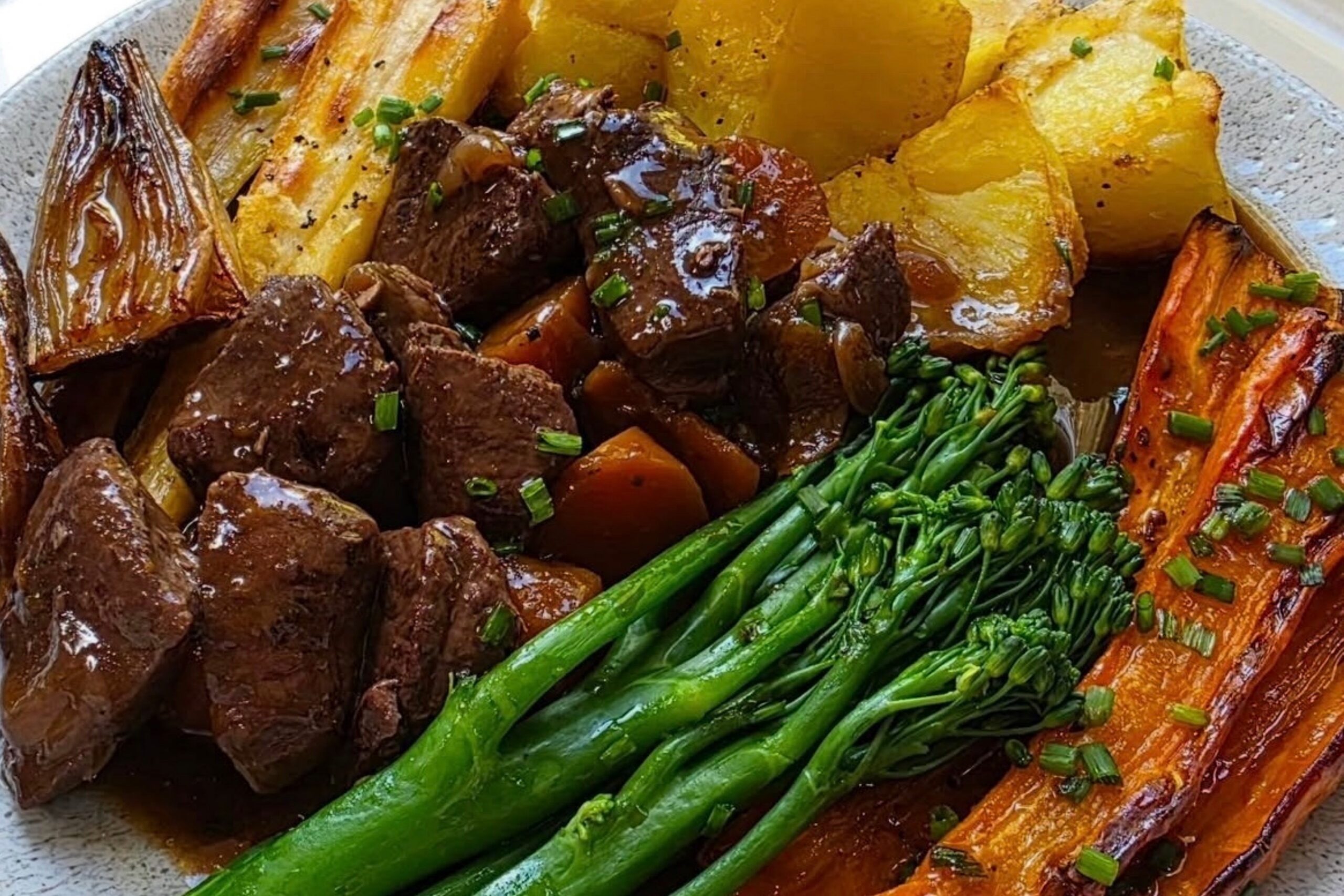 A plate of venison stew served with carrots, tenderstem broccoli and potatoes.